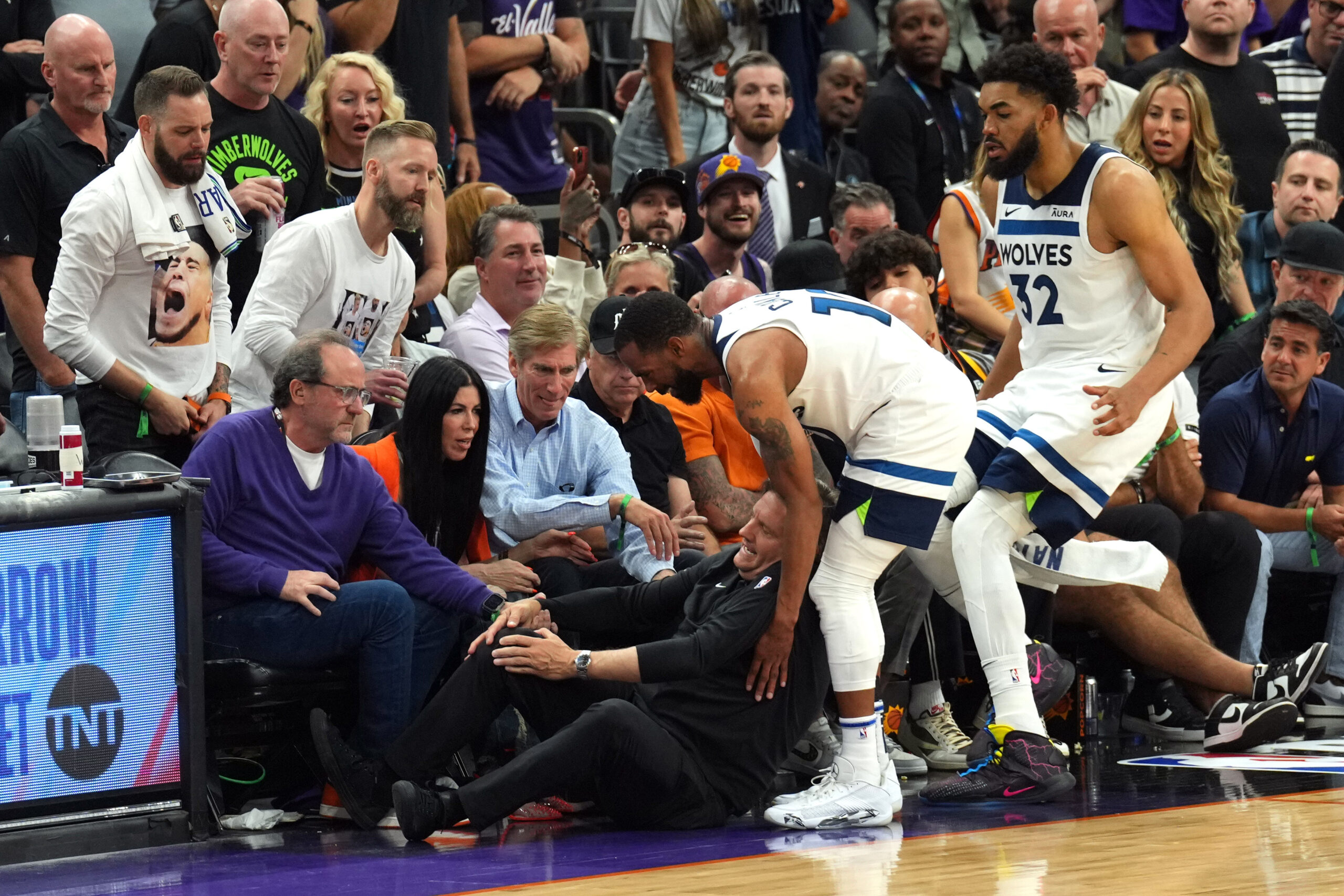 Apr 28, 2024; Phoenix, Arizona, USA; Minnesota Timberwolves guard Mike Conley (10) and Minnesota Timberwolves center Karl-Anthony Towns (32) tend to head coach Chris Finch after he was injured during the second half of game four of the first round for the 2024 NBA playoffs against the Phoenix Suns at Footprint Center. Mandatory Credit: Joe Camporeale-USA TODAY Sports