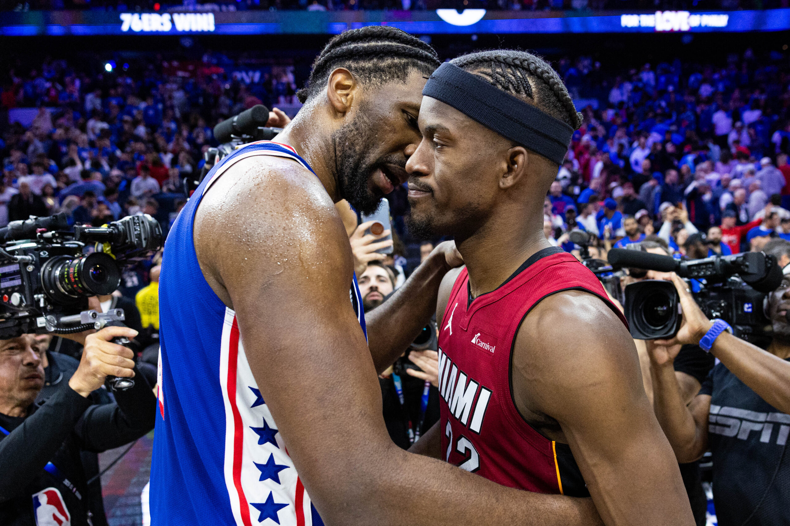 Apr 17, 2024; Philadelphia, Pennsylvania, USA; Philadelphia 76ers center Joel Embiid (21) hugs Miami Heat forward Jimmy Butler (22) on the court after a 76ers victory in a play-in game of the 2024 NBA playoffs at Wells Fargo Center. Mandatory Credit: Bill Streicher-USA TODAY Sports