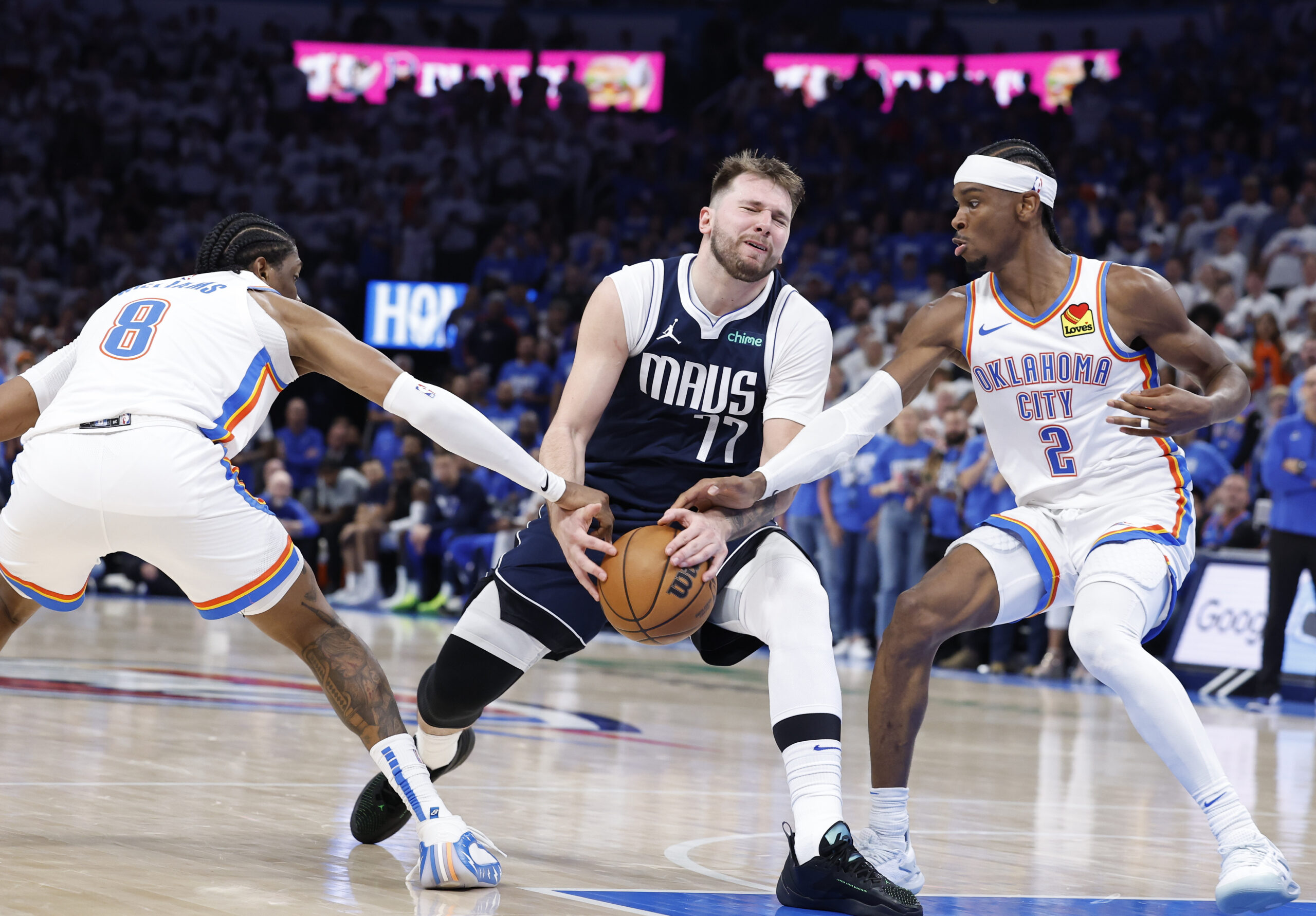 May 7, 2024; Oklahoma City, Oklahoma, USA; Dallas Mavericks guard Luka Doncic (77) has the ball stripped as he drives between Oklahoma City Thunder guard Shai Gilgeous-Alexander (2) and forward Jalen Williams (8) during the second half of game one of the second round for the 2024 NBA playoffs at Paycom Center. Mandatory Credit: Alonzo Adams-USA TODAY Sports